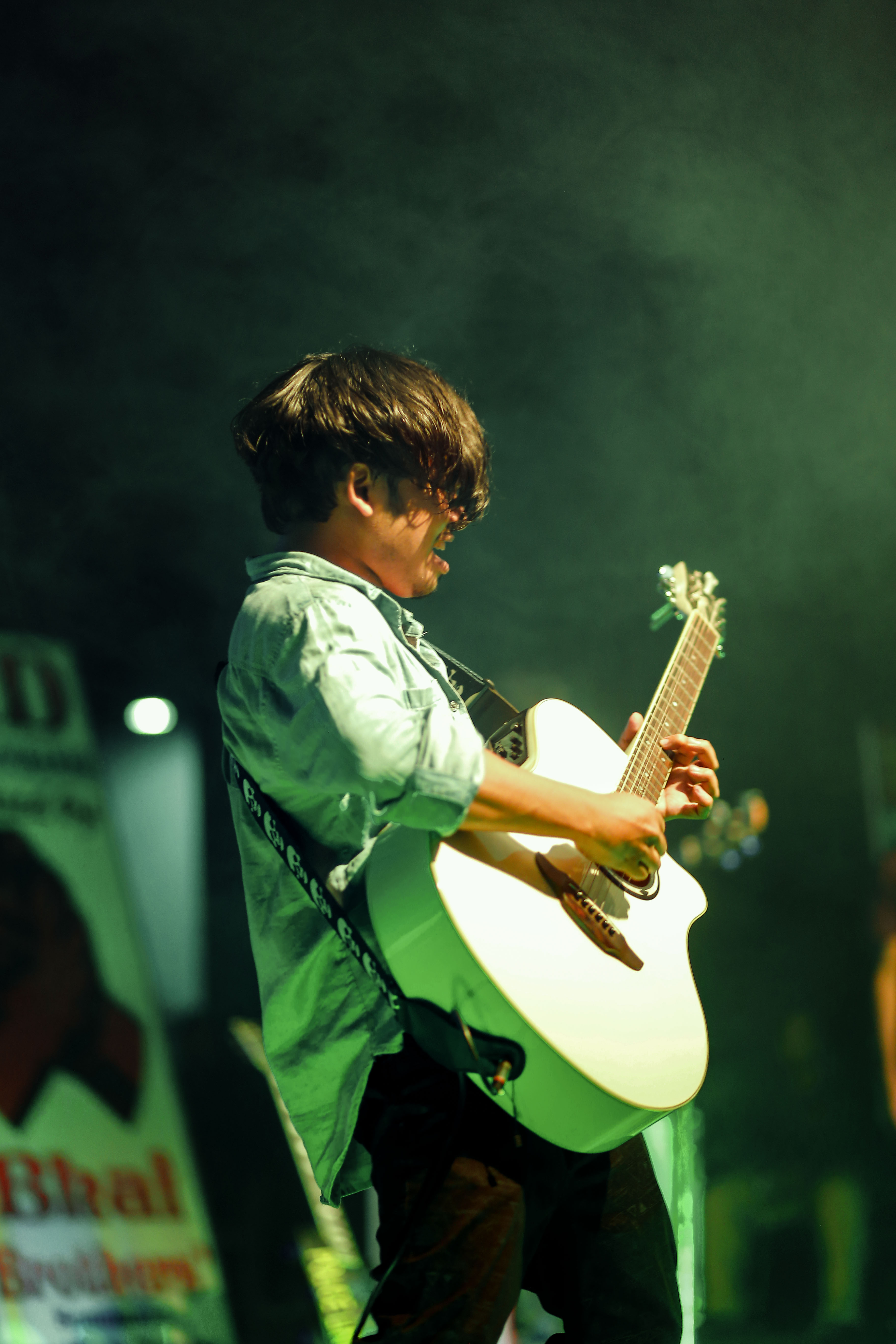 Samee performing with acoustic guitar on stage